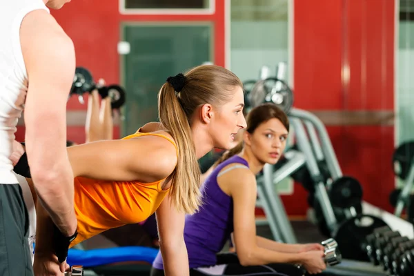 Personas en el gimnasio haciendo ejercicio con pesas — Foto de Stock