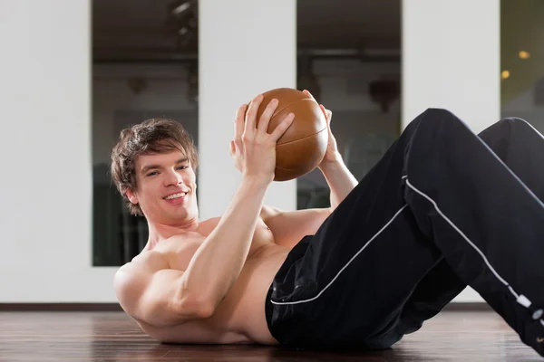 El hombre está haciendo ejercicio con balón de medicina en el gimnasio —  Fotos de Stock