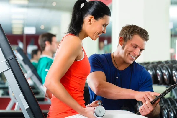 Frau und Personal Trainer im Fitnessstudio mit Kurzhanteln — Stockfoto
