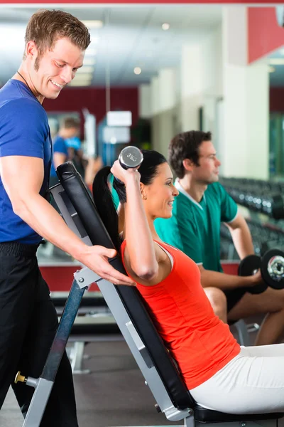 Mujer y Entrenador Personal en gimnasio con mancuernas — Foto de Stock