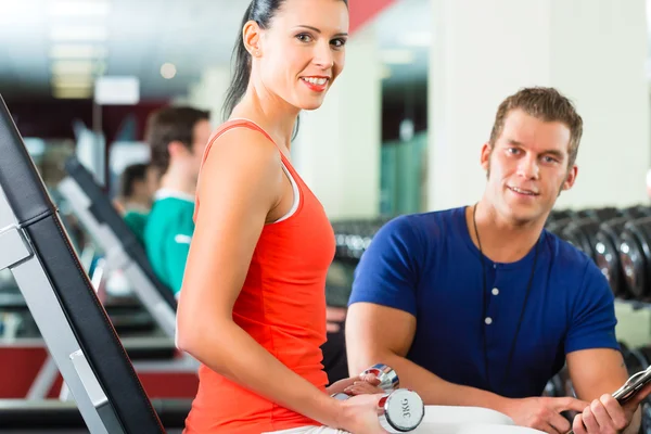 Vrouw en persoonlijke trainer in de sportschool met halters — Stockfoto