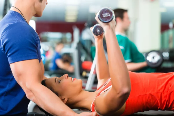 Vrouw en persoonlijke trainer in de sportschool met halters — Stockfoto