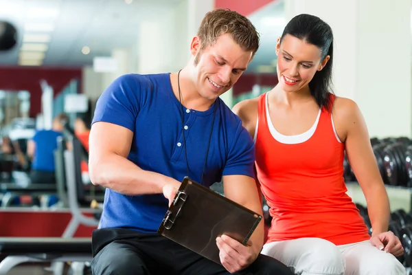 Mulher e personal trainer no ginásio com halteres — Fotografia de Stock