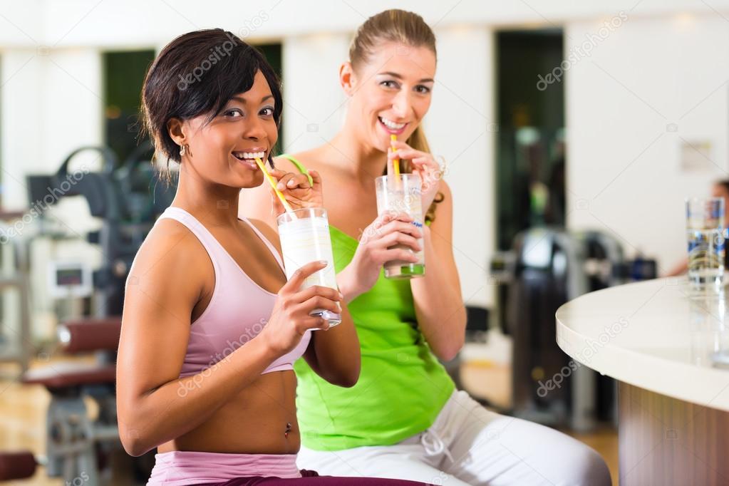 women in the gym drinking a isotonic drink