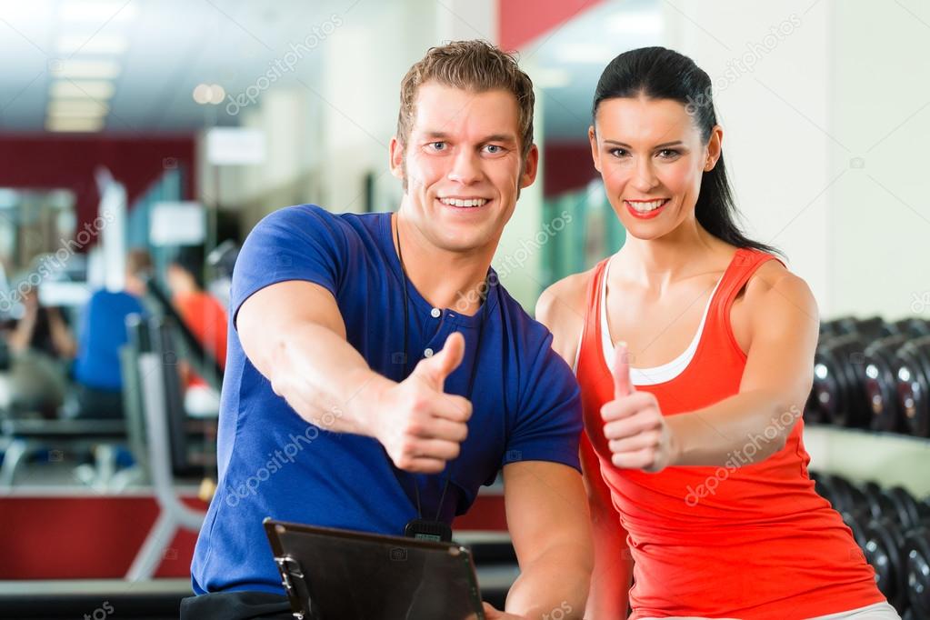 Woman and Personal Trainer in gym with dumbbells