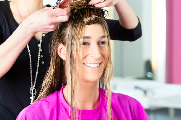 Woman receiving haircut from hair stylist or hairdresser Stock Image