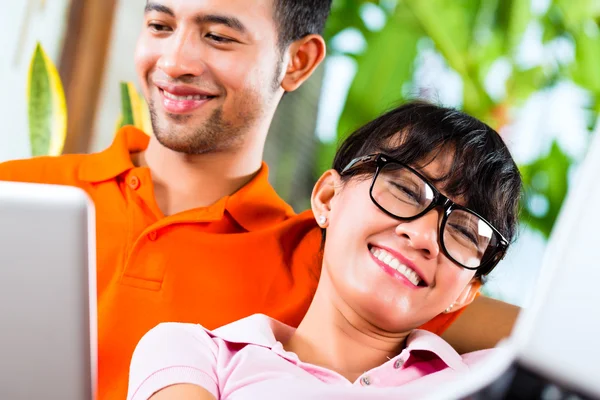 Asiatisch pärchen auf die couch mit ein laptop — Stockfoto