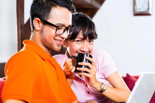 Asian couple on the couch with a laptop — Stock Photo, Image