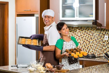 Asian couple baking cake in home kitchen