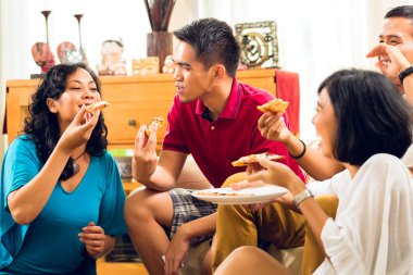 Asian people eating pizza at party