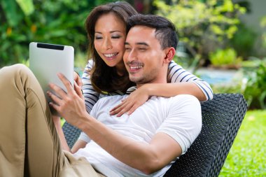 Asian couple outdoor with a tablet pc clipart