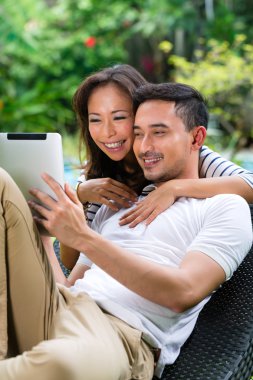 Asian couple outdoor with a tablet pc clipart