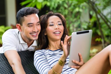 Asian couple outdoor with a tablet pc