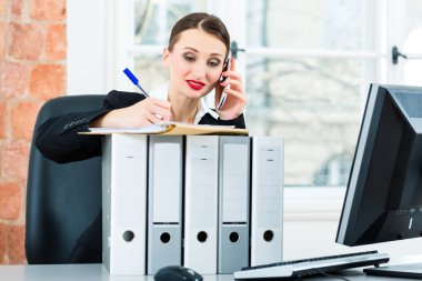 businesswoman in office makes notes in a file