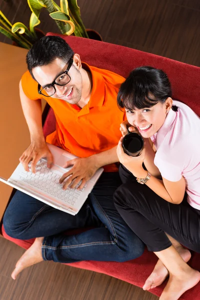 Asian couple on the couch with a laptop — Stock Photo, Image