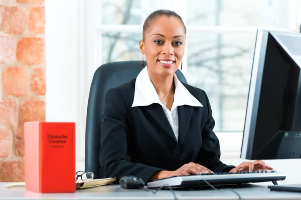 Rechtsanwältin in ihrem Büro mit Gesetzesbuch am Computer — Stockfoto