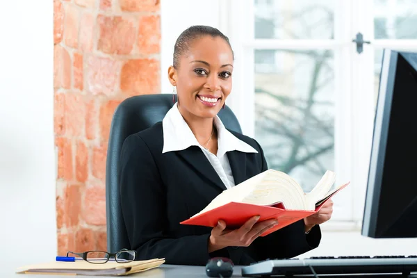 Lawyer in her office with law book on computer — Stock fotografie