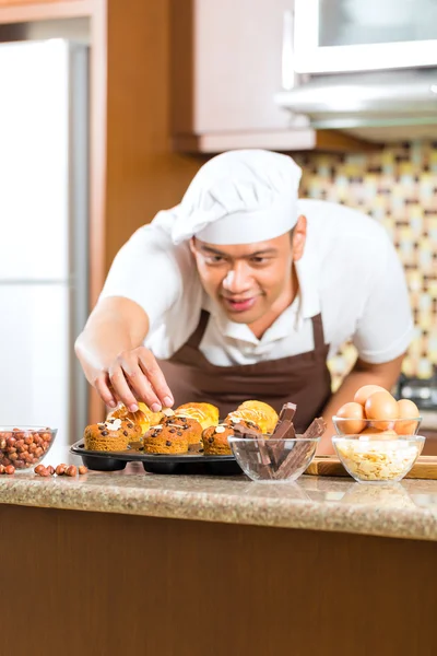 Hombre asiático hornear magdalenas en casa cocina — Foto de Stock