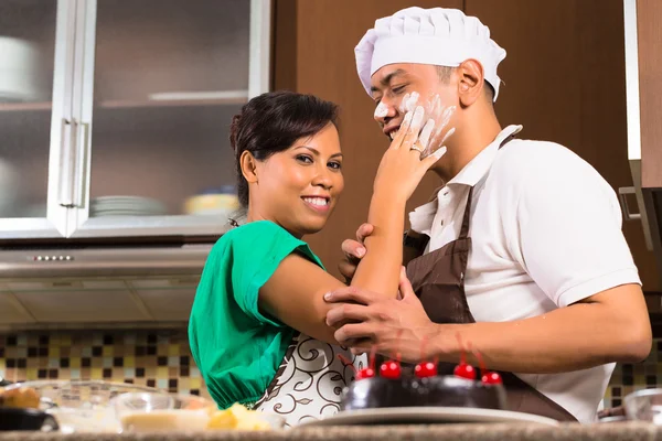 Asian couple baking chocolate cake in kitchen — ストック写真
