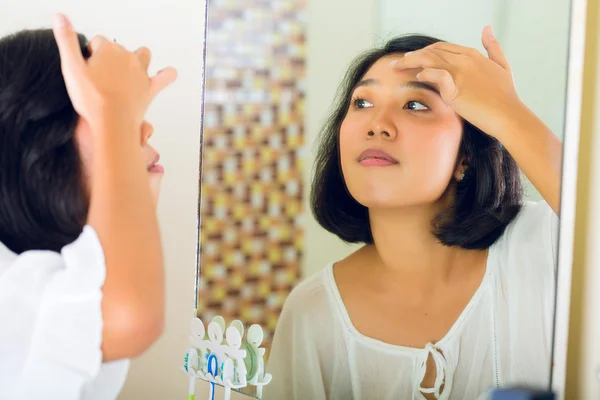 Asian woman discovering a pimple in face — стокове фото