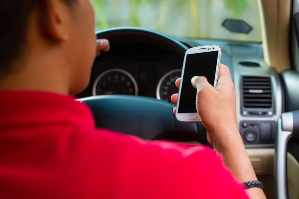 Asian man texting while driving — Stok fotoğraf