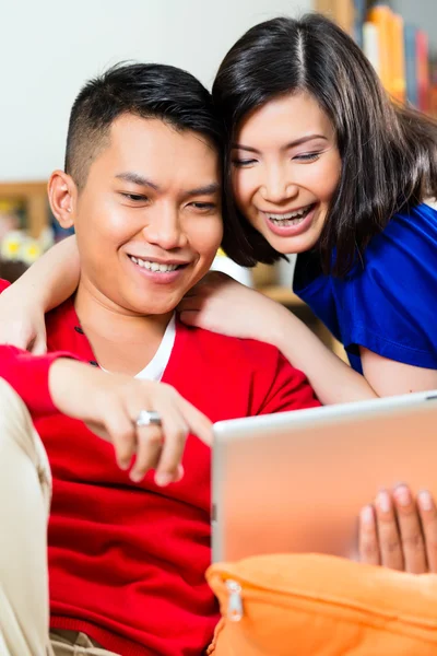 Casal indonésio sentado com um tablet — Fotografia de Stock