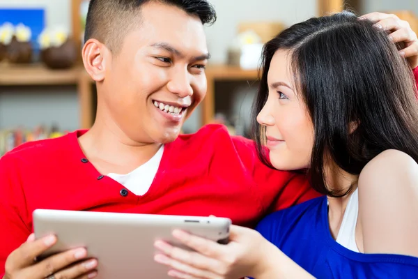 Casal indonésio sentado com um tablet — Fotografia de Stock