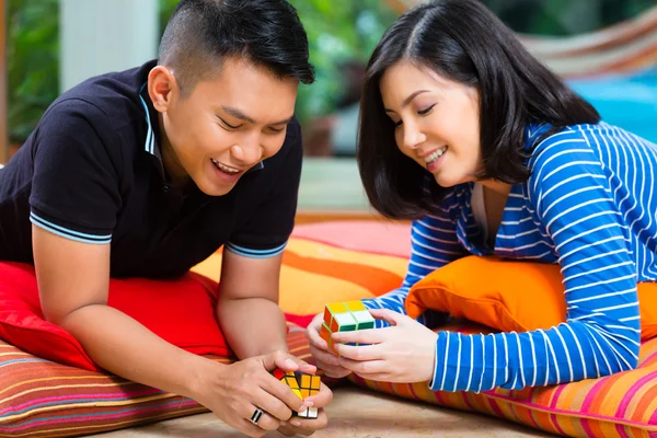 Casal asiático em casa jogando com cubo mágico — Fotografia de Stock