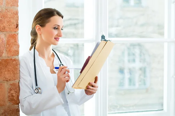 Doctor in clinic writing in a file — Stok fotoğraf