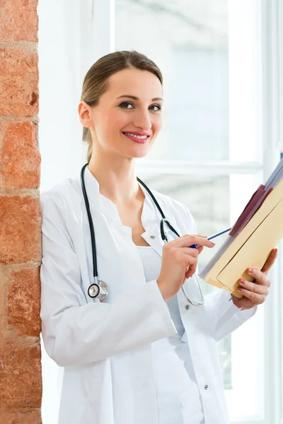 Doctor in clinic writing in a file — 图库照片