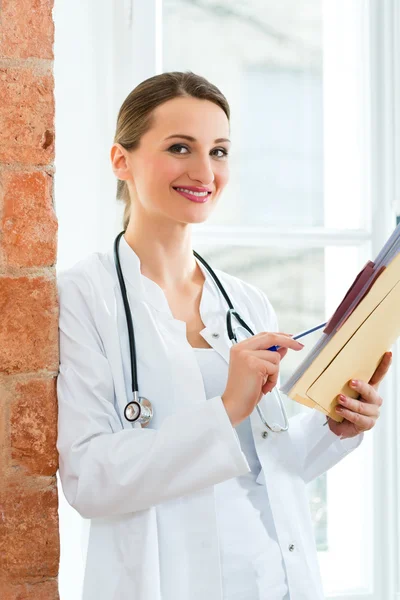 Doctor in clinic writing in a file — ストック写真