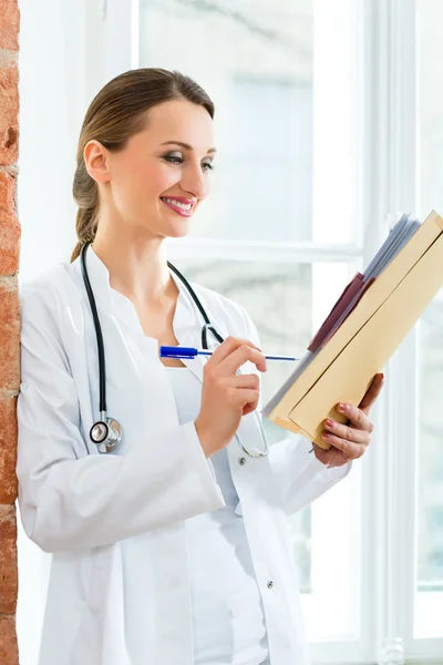 Doctor in clinic writing in a file — Stok fotoğraf