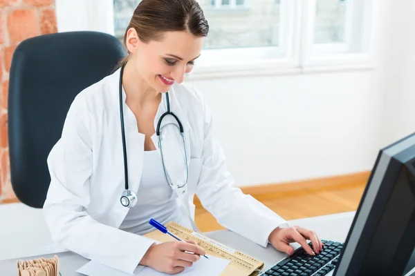 Arzt am Schreibtisch in der Klinik schreibt eine Akte oder ein Dossier — Stockfoto