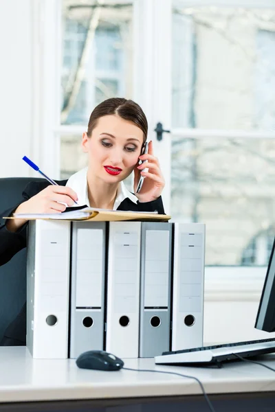 Businesswoman in office makes notes in a file — ストック写真