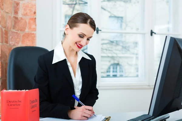 Lawyer in office with law book — Stockfoto