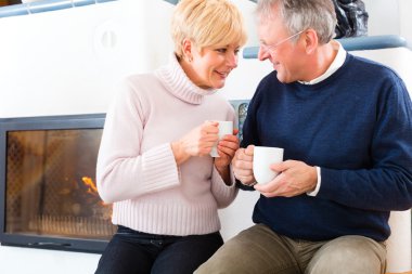 Çay bardağı ile şömine önünde evde yaşlılar
