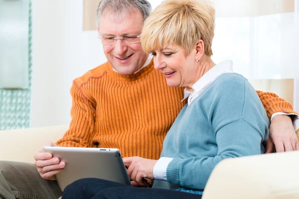 Пенсионеры дома с планшетным компьютером — стоковое фото