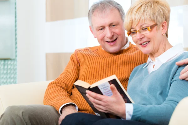 Mayores en casa leyendo un libro juntos — Foto de Stock