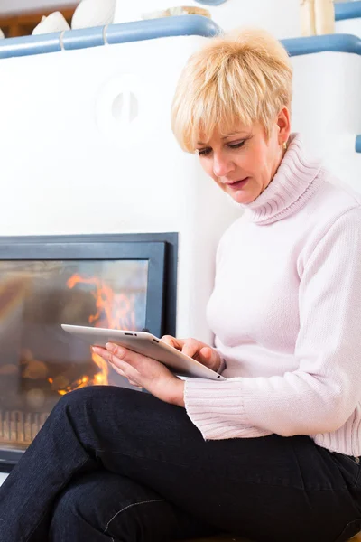 Seniorin zu Hause vor Kamin — Stockfoto