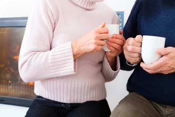 Senioren zu Hause vor Kamin mit Teetasse — Stockfoto