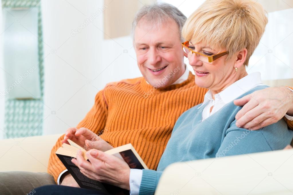 Seniors at home reading a book together