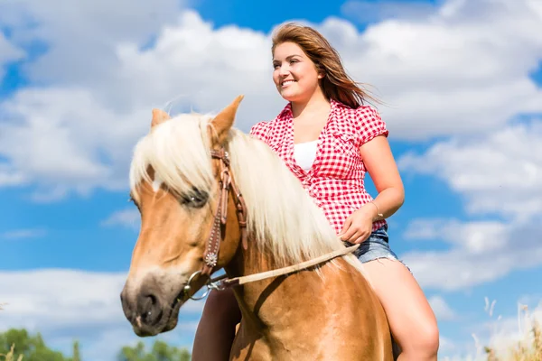 Vrouw rijden op paard in zomer weide — Stockfoto