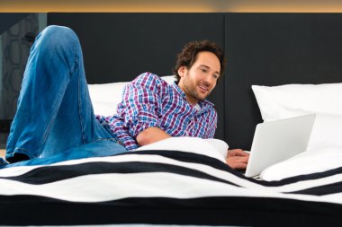 man in Hotel in bed with wifi and computer