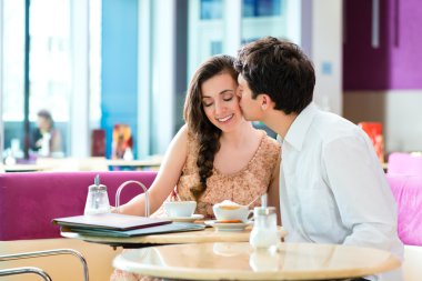Sarılma ve öpüşme genç çift Cafe