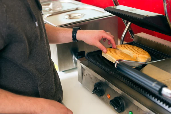 Vendedor haciendo hotdog en snack bar de comida rápida — Foto de Stock