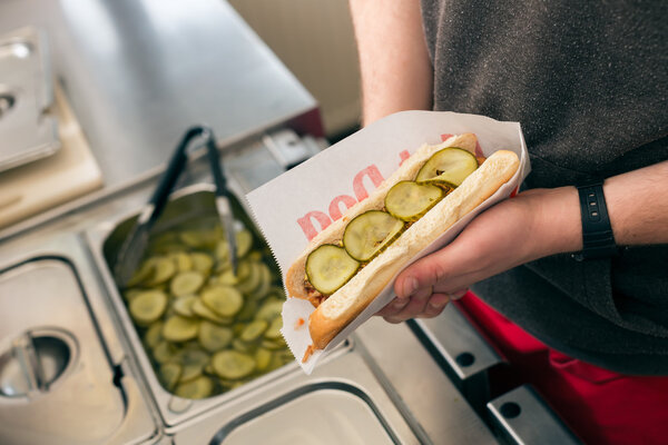 salesman making hotdog in fast food snack bar