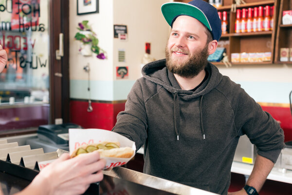 salesman with hotdog in fast food snack bar