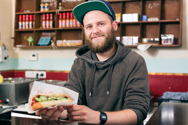 salesman with hotdog in fast food snack bar