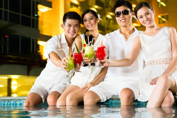 Čínské páry pití koktejlů v baru u bazénu hotelu — Stock fotografie