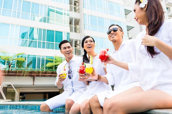 Amigos asiáticos sentados en la piscina del hotel — Foto de Stock